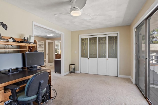 carpeted office space featuring baseboards and a ceiling fan