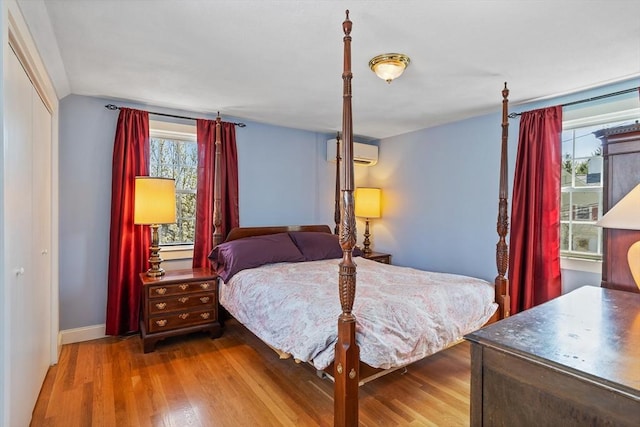 bedroom with baseboards, a wall mounted air conditioner, wood finished floors, and vaulted ceiling