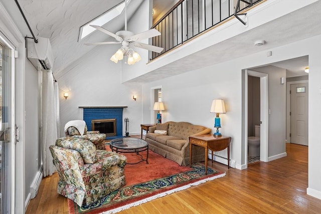 living area featuring baseboard heating, a ceiling fan, baseboards, and wood finished floors