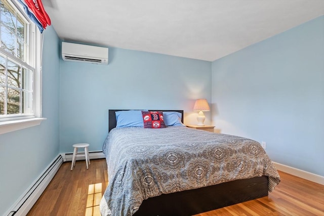 bedroom with multiple windows, a baseboard heating unit, a wall mounted air conditioner, and wood finished floors