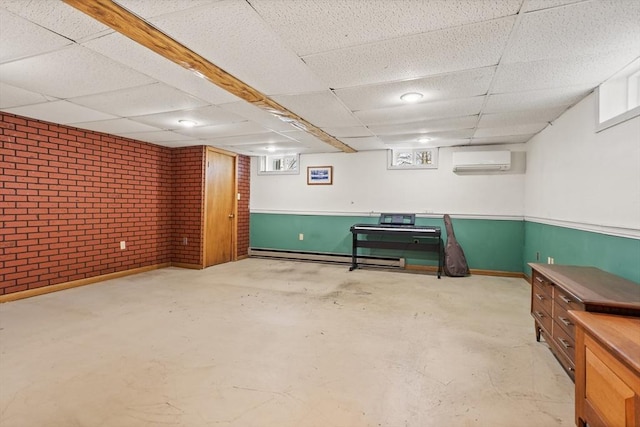 below grade area with an AC wall unit, brick wall, a baseboard heating unit, and a drop ceiling