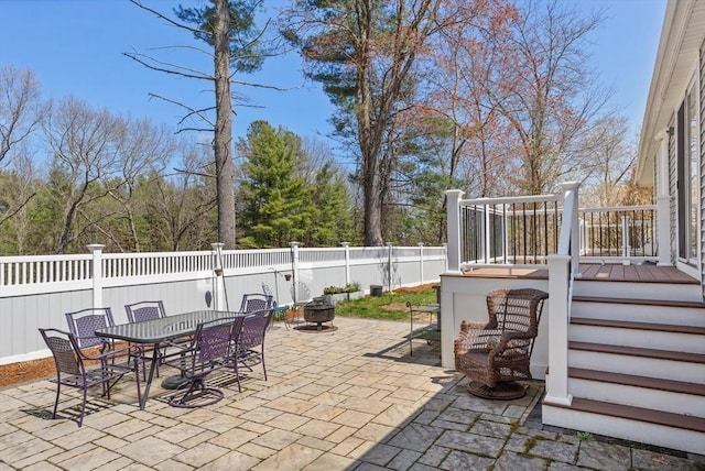 view of patio / terrace with a fenced backyard, outdoor dining space, a fire pit, and a wooden deck