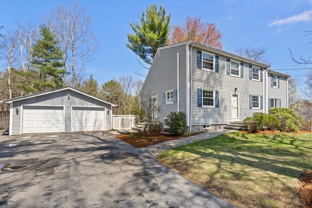 colonial inspired home featuring a detached garage, an outdoor structure, and a front lawn