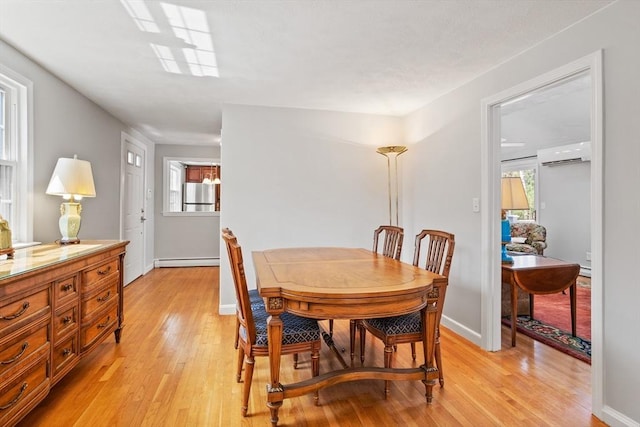 dining area with light wood-style floors, baseboards, a wall unit AC, and baseboard heating