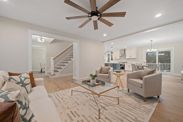 living room with ceiling fan with notable chandelier and light wood-type flooring