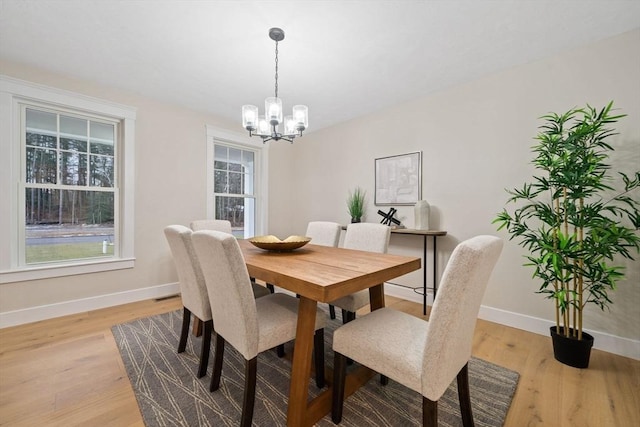 dining area with light hardwood / wood-style floors and a chandelier