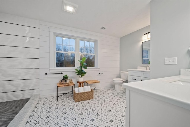 bathroom with vanity, toilet, and wood walls