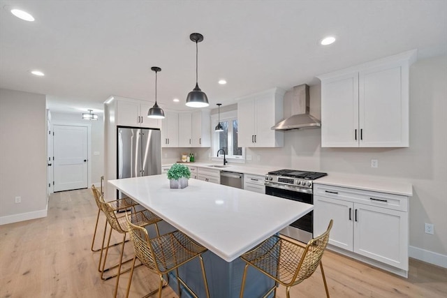 kitchen featuring white cabinets, appliances with stainless steel finishes, sink, and wall chimney range hood