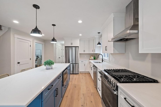 kitchen featuring wall chimney exhaust hood, stainless steel appliances, sink, and white cabinets