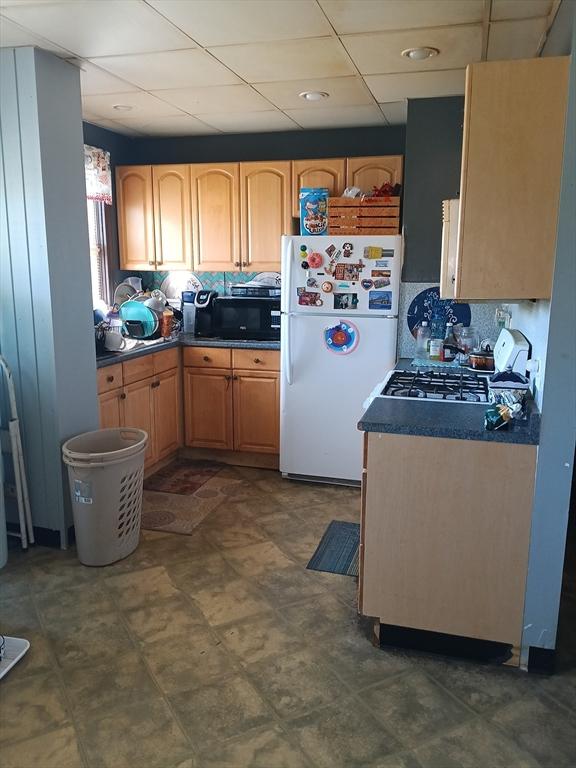 248 S Main St, Attleboro, MA 02703 - kitchen featuring freestanding refrigerator, black microwave, a drop ceiling, and dark countertops