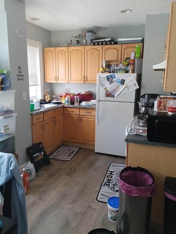 248 S Main St, Attleboro, MA 02703 - kitchen featuring freestanding refrigerator, black microwave, wood finished floors, and a textured ceiling