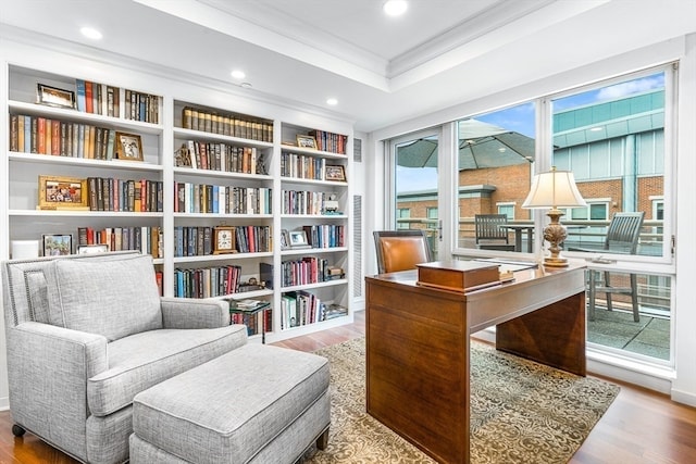 sitting room featuring hardwood / wood-style floors, crown molding, a raised ceiling, and built in shelves