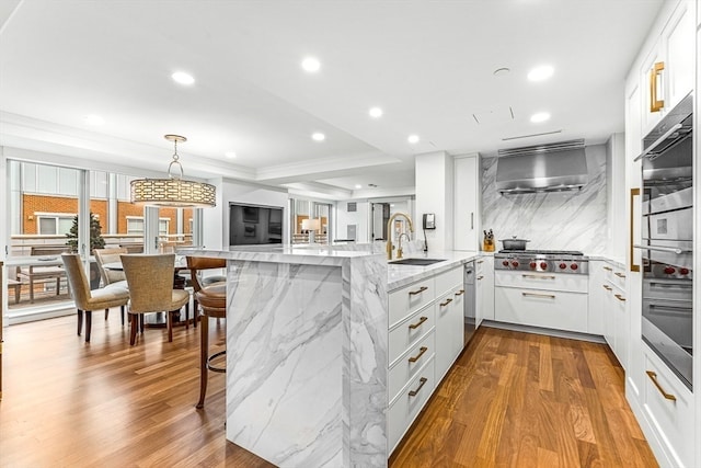 kitchen with wall chimney range hood, sink, a kitchen breakfast bar, white cabinets, and kitchen peninsula