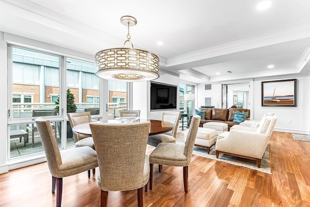 dining area with crown molding, a tray ceiling, and light hardwood / wood-style floors