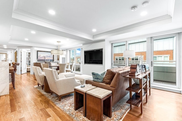 living room featuring a raised ceiling, crown molding, and light hardwood / wood-style floors