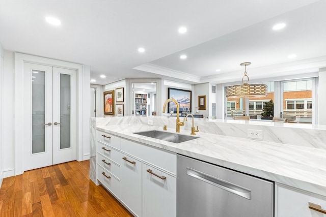 kitchen with french doors, sink, white cabinetry, wood-type flooring, and hanging light fixtures