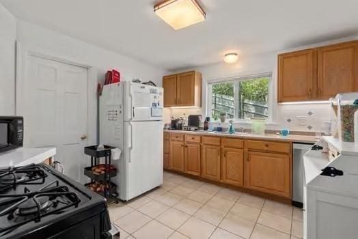 kitchen featuring a sink, light countertops, black appliances, and light tile patterned flooring