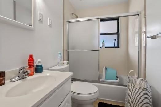 full bath with bath / shower combo with glass door, vanity, and toilet