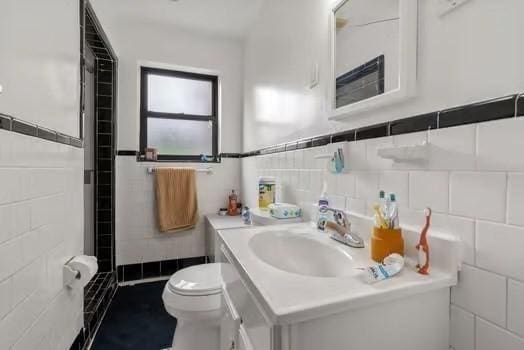 full bathroom featuring vanity, tile walls, walk in shower, and toilet