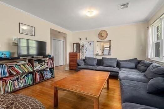 living area with visible vents and wood finished floors