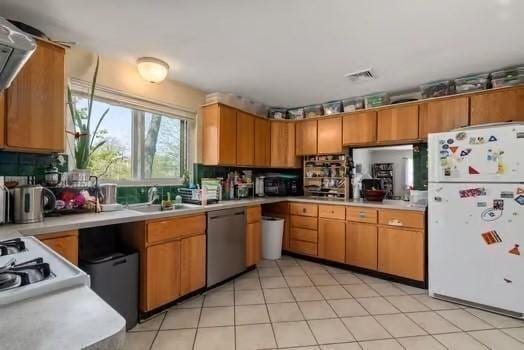 kitchen featuring light countertops, freestanding refrigerator, visible vents, dishwasher, and a sink