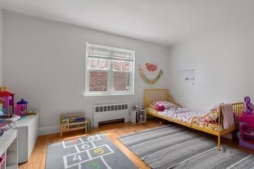 bedroom featuring wood finished floors and radiator heating unit