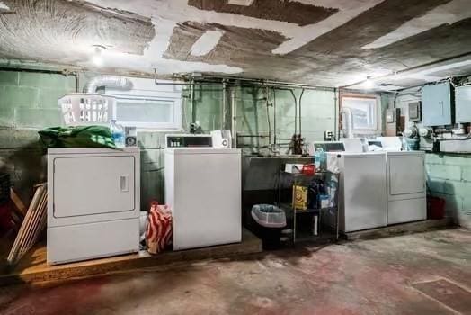 below grade area with independent washer and dryer, concrete block wall, and electric panel