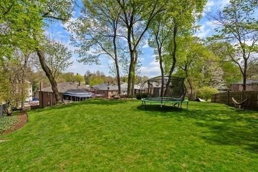 view of yard featuring a trampoline and fence