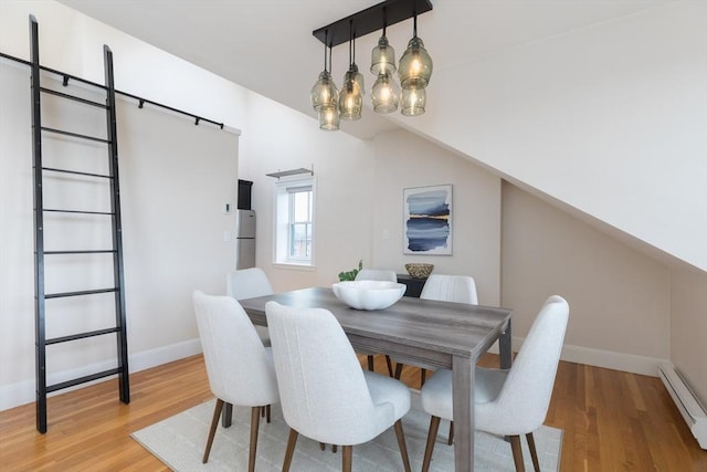 dining space featuring a baseboard heating unit, lofted ceiling, and light hardwood / wood-style flooring