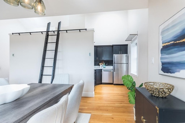 kitchen featuring light wood-type flooring, appliances with stainless steel finishes, and decorative backsplash