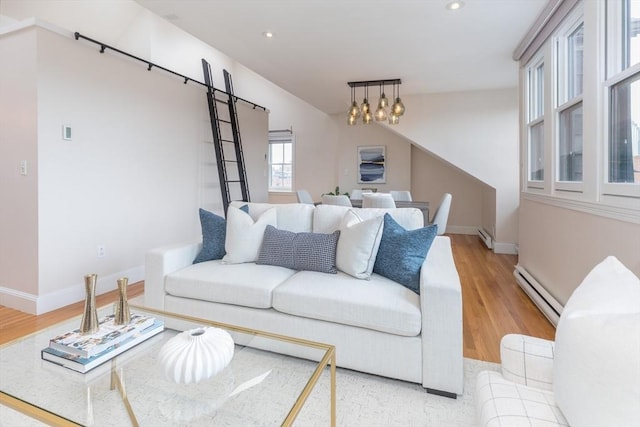 living room with baseboard heating, an inviting chandelier, and light hardwood / wood-style floors