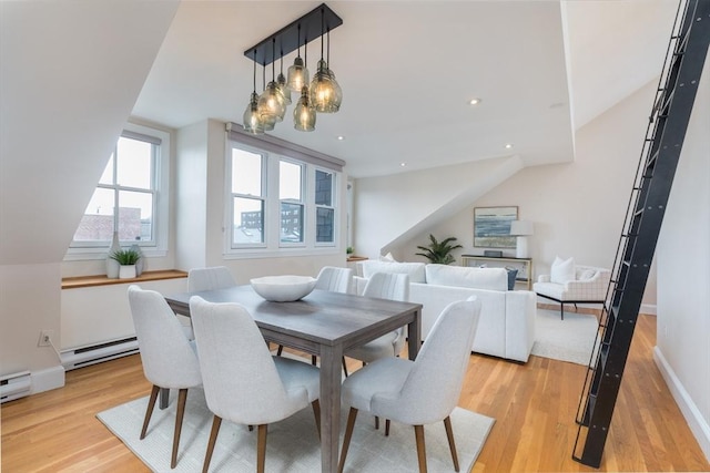 dining room featuring a baseboard radiator, vaulted ceiling, an inviting chandelier, and light wood-type flooring