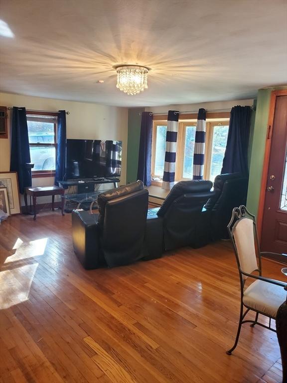 living room featuring plenty of natural light, wood-type flooring, and a notable chandelier