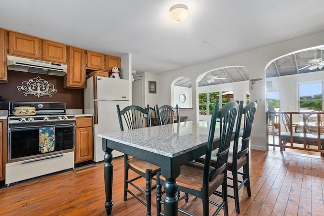 52 Lake Shore Dr, Essex, MA 01929 - kitchen with under cabinet range hood, stove, freestanding refrigerator, ceiling fan, and hardwood / wood-style floors