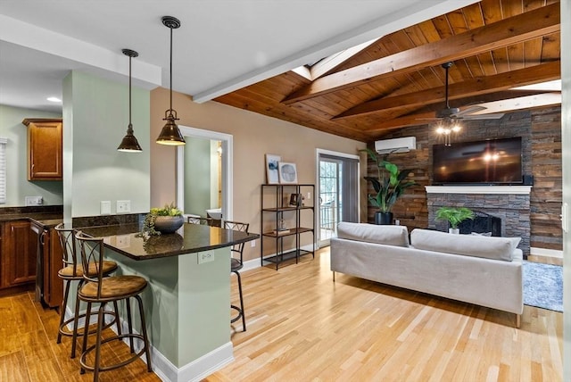 living room with light wood finished floors, vaulted ceiling with skylight, a fireplace, and an AC wall unit