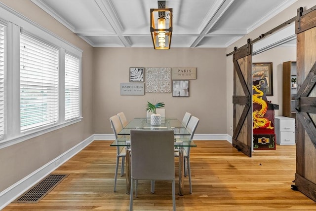 dining space featuring light wood finished floors, a barn door, visible vents, and coffered ceiling