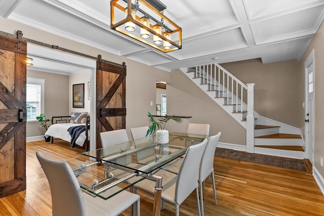 dining space with a barn door, stairway, coffered ceiling, and wood finished floors