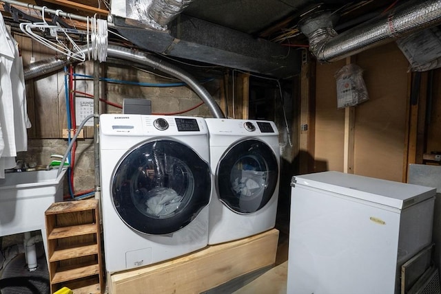 clothes washing area with laundry area, washer and clothes dryer, and a sink