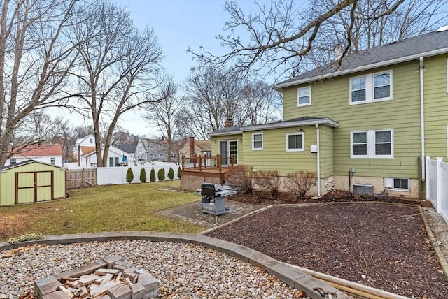 view of yard with an outbuilding, a fenced backyard, a storage shed, central AC, and a wooden deck