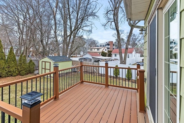 wooden deck featuring a yard, a storage shed, a residential view, a fenced backyard, and an outdoor structure