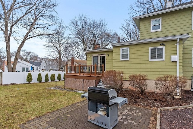 rear view of house featuring a yard, a wooden deck, fence, and a patio