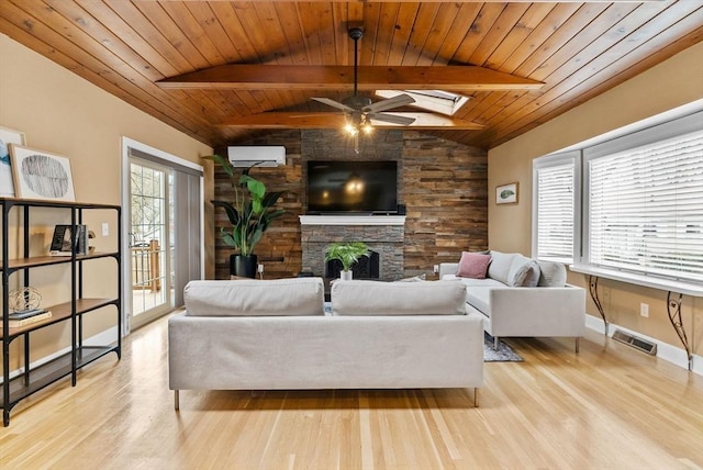 living area featuring vaulted ceiling with skylight, visible vents, a fireplace, and wood finished floors