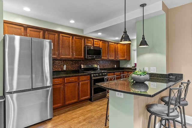 kitchen with stainless steel appliances, a breakfast bar, a peninsula, light wood-style floors, and tasteful backsplash