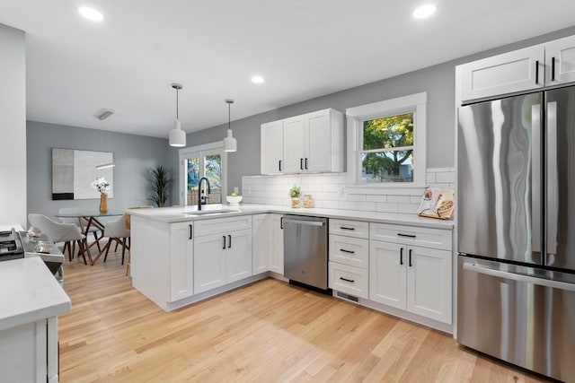 kitchen featuring appliances with stainless steel finishes, pendant lighting, white cabinets, and plenty of natural light