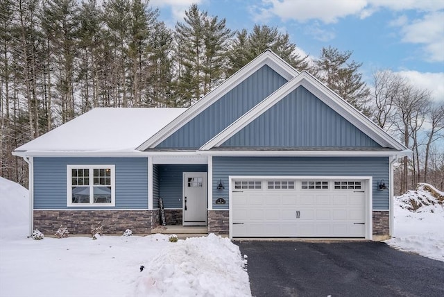 craftsman house featuring board and batten siding, stone siding, driveway, and an attached garage