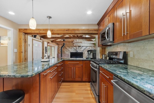 81 Baldwin Rd, Billerica, MA 01821 - kitchen with stainless steel appliances, brown cabinets, light wood-style flooring, decorative backsplash, and a peninsula