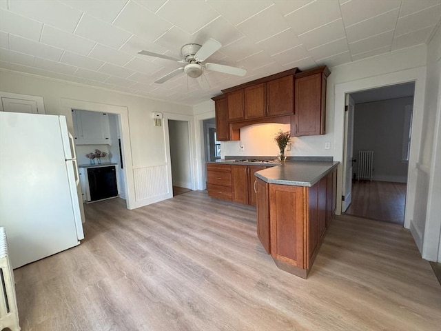 kitchen with radiator, ceiling fan, light wood-type flooring, white fridge, and kitchen peninsula