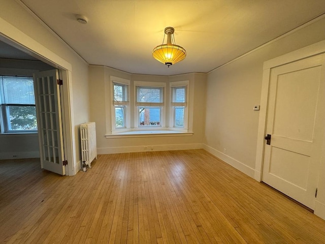 spare room featuring light wood-type flooring and radiator