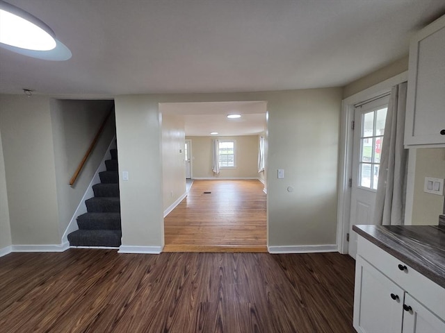 interior space featuring dark wood-style flooring, baseboards, and stairway