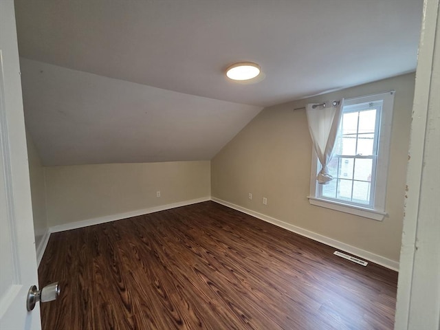 bonus room featuring baseboards, visible vents, lofted ceiling, and dark wood-type flooring